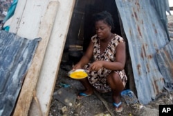FILE - Nathanaelle Bernard, 19 and pregnant, cooks an omelet in a makeshift hut shared with five family members in Coteaux, Haiti, Nov. 1, 2016. Hurricane Matthew destroyed her home weeks earlier.