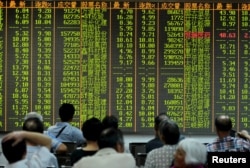 Investors look at stock information on an electronic board at a brokerage house in Hangzhou, Zhejiang province, Aug. 25, 2015.
