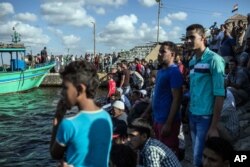 Egyptians wait on shore as a coast guard boat arrives carrying the bodies of migrants from a Europe-bound boat that capsized off Egypt’s Mediterranean coast, in Rosetta, Egypt, Sept. 22, 2016.