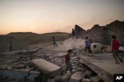 FILE - Children play on debris in a neighborhood retaken by Iraqi security forces during fighting against Islamic State militants in West Mosul, Iraq, June 25, 2017.
