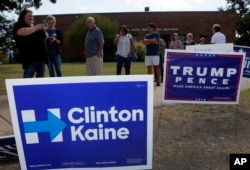 Early voters stand by campaign signs as they wait in line at a voting location in Dallas, Texas, Oct. 27, 2016.