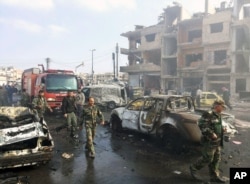 In this photo released by the Syrian official news agency SANA, Syrian citizens gather at the scene where two blasts exploded in the pro-government neighborhood of Zahraa, in Homs province, Syria, Feb. 21, 2016.