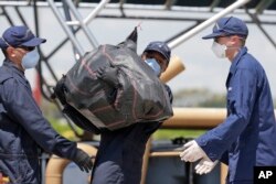 FILE - Members of the U.S. Coast Guard offload bails of over eight tons of cocaine interdicted in international waters, from the Cutter Bernard C. Webber at Coast Guard Station Miami Beach, June 13, 2016, in Miami Beach, Fla. The drugs were collected in the eastern Pacific Ocean off the coast of Central and South America over two months, the Coast Guard said.