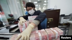 中国江苏省南通市一家银行的职员戴着口罩整理人民币钞票。（2020年1月30日）