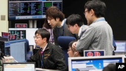 In this photo provided by the Japan Aerospace Exploration Agency (JAXA), staff of the Hayabusa2 Project watch monitors for a safety check at the control room of the JAXA Institute of Space and Astronautical Science in Sagamihara, near Tokyo, Feb. 21.