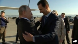 FILE - In this Dec. 11, 2017, frame grab made available by Russian Presidential TV Syrian President Bashar al-Assad, right, greets Russian President Vladimir Putin upon his arrival to the Hemeimeem air base in Syria.