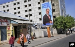 Somalis walk past a campaign poster for candidate Mohamed Abdullahi Farmaajo on the eve of presidential elections in Mogadishu, Somalia, Feb. 7, 2017. Graft - vote-buying, fraud, intimidation - is the top concern in a nation that Transparency International now rates as the most corrupt in the world.