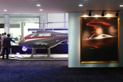 FILE - An unmanned helicopter drone AV500 and a painting of a drone are seen at a stand for the China National Aero-Technology Import & Export Corp., at a military drone expo in Abu Dhabi, United Arab Emirates, Feb. 25, 2018.