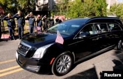 FILE - Law enforcement officers salute the hearse carrying the body of Ventura County Sheriff Sgt. Ron Helus, who was shot and killed in a mass shooting at a bar in Thousand Oaks, Calif., Nov. 8, 2018.