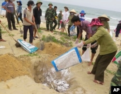 FILE- Villagers bury dead fish on a beach in Quang Binh, Vietnam.