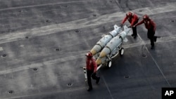 FILE - U.S. Navy sailors push ammunition across the deck of the U.S.S. Dwight D. Eisenhower aircraft carrier, Nov. 21, 2016, as the ship carries out military operations against IS extremists in Syria and Iraq.