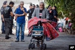 FILE - A man carries his belongings and his dog as he leaves a Gypsy camp to be evacuated and demolished in Rome, Sept. 9, 2010.