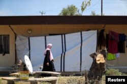 A Libyan displaced woman, who fled her house because of the fighting between the Eastern forces commanded by Khalifa Haftar and the internationally recognized government, walks at an industrial complex which is used as a shelter, in Tripoli, Libya, April