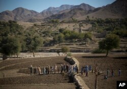 FILE - Afghan villagers take a break after preparing the soil for their poppy seeds in fields in Cham Kalai village in Afghanistan's eastern Nangarhar province, an area which is largely controlled by Taliban, Nov. 12, 2013.
