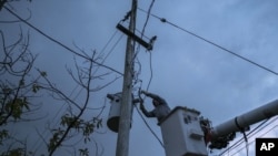 En esta imagen, tomada el 12 de julio de 2018, un operario de la Autoridad de Energía Eléctrica de Puerto Rico trabaja para restaurar el suministro de energía eléctrica en Adjuntas, Puerto Rico. La red eléctrica de Puerto Rico arrastra problemas desde que Irma recorrió parte de la isla como un huracán de categoría cinco el 6 de septiembre, y luego del impacto directo de María, de categoría cuatro, dos semanas después, dañando hasta el 75% de las líneas de transmisión.