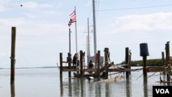 Locals raise the American flag atop a broken port in Islamorada, Fla.. (R. Taylor/VOA)