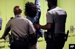 A protester is escorted out of commencement exercises during a speech by Education Secretary Betsy DeVos at Bethune-Cookman University in Daytona Beach, Florida, May 10, 2017.