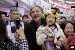 Chief Executive candidate, Hong Kong's former Financial Secretary John Tsang Chun-wah, center, holds a child as he poses for a photograph with his supporters at a election campaign in Hong Kong, March 16, 2017.
