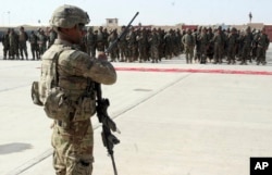 FILE - A U.S. military personal stands guard during a graduation ceremony for Afghan troops, in Lashkargah, capital of southern Helmand province, Afghanistan, July 24, 2016.
