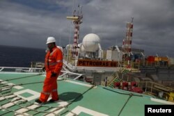 FILE - A worker walks on the heliport at the Brazil's Petrobras P-66 oil rig in the offshore Santos basin in Rio de Janeiro, Brazil, Sept. 5, 2018.
