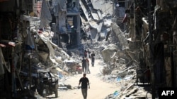 Palestnci prolaze kroz ruševine u Kan Junisu, 11. jun 2024. (Eyad BABA / AFP)