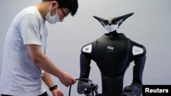 A staff member of Telexistence checks the company's shelf-stacking avatar robot, designed to resemble a kangaroo and developed to work in a convenience store in Tokyo, Japan July 3, 2020. (REUTERS/Issei Kato)