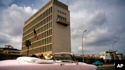 Tourists take a ride in a vintage car as they pass the U.S. embassy in Havana, Cuba, March 18, 2019. 