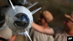 In this photo taken from Russian Defense Ministry official web site on Tuesday, Oct. 6, 2015, Russian military support crew inspect missiles attached to their jet at an air base in Syria. at an air base Hmeimim in Syria.