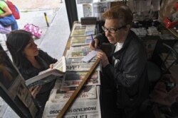 FILE - A woman buys printed newspapers at a kiosk in Caracas, Venezuela, July 3, 2019.