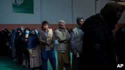 People wait in a line to receive cash at a money distribution organized by the World Food Program in Kabul, Afghanistan, Nov. 3, 2021.
