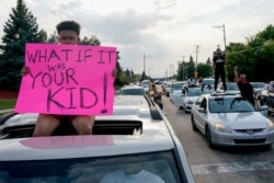 A protester sits on a car as they stop traffic, Aug. 24, 2020, in Kenosha, Wis. Wisconsin Gov. Tony Evers has summoned the National Guard to head off another round of violent protests.