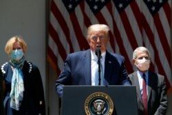 President Donald Trump speaks about the coronavirus in the Rose Garden of the White House, May 15, 2020, in Washington, as Coronavirus Task Force members Dr. Anthony Fauci and Dr. Deborah Birx listen.