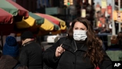 A woman who declined to give her name wears a mask, Jan. 30, 2020, in New York. She works for a pharmaceutical company and said she was concerned about coronavirus infection. "I'd wear a mask if I were you," she said. 