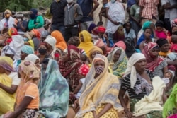 FILE - Families wait outside the port of Pemba for a boat to be evacuated from Palma, April 1, 2021.