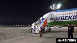 People disembark from a plane upon their arrival from Syria at an airport in Tashkent, Uzbekistan, April 30, 2021. Uzbekistan brought home women and children from Syria where they had been staying at camps with other families of Islamic State fighters.