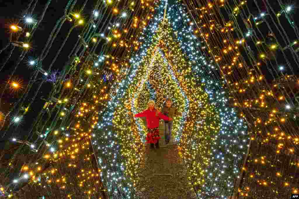 Dos niños pasan frente a las 200.000 luces que decoran el paraíso invernal de Naumkeag, Stockbridge, Massachusetts, el 13 de diciembre de 2020. [AFP]