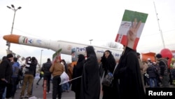 FILE - People are seen gathered around a model of Simorgh satellite-carrier rocket displayed during a ceremony marking the 37th anniversary of the Islamic Revolution, in Tehran, Iran, Feb. 11, 2016. 