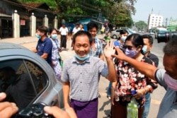 AP journalist Thein Zaw, center, waves outside Insein prison after his release, March 24, 2021, in Yangon, Myanmar. Thein Zaw was arrested last month while covering a protest against the coup in Myanmar.