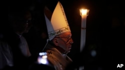 Pope Francis presides over a solemn Easter vigil ceremony in St. Peter's Basilica at the Vatican, April 15, 2017. Holding a single candle, Francis moved down the center aisle of a darkened St. Peter's Basilica, symbolizing the darkness that fell after Jesus' crucifixion on Good Friday.