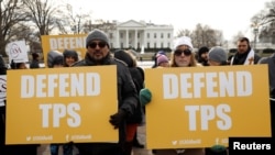 Demonstrators hold signs protesting the termination of Salvadorans' Temporary Protected Status