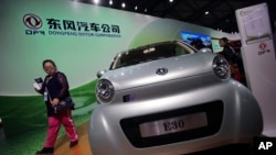 FILE - A visitor looks at an E30 EV, a small electric vehicle of Chinese state-owned automobile manufacturer Dongfeng Motor Co., at China International Industry Fair in Shanghai, Nov. 5, 2013. 