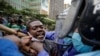 Kenyan policemen grab a protester by the throat as they detain him at a demonstration in downtown Nairobi, Kenya, July 7, 2020.