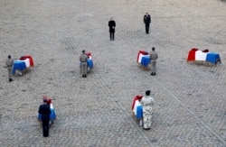 FILE - French President Emmanuel Macron pays his respect in front of the flag-draped coffins of the thirteen French soldiers killed in Mali, during a ceremony at the Hotel National des Invalides in Paris, Dec. 2, 2019.