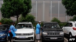 FILE - Medical technicians administer COVID-19 swab tests at a drive-through testing site at Wits University, Braamfontein, Johannesburg, South Africa, Jan. 5, 2021.