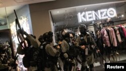 FILE - A police officer aims his weapon during an anti-government protest inside a mall, in Hong Kong, Dec. 15, 2019.