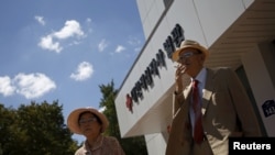 Oh Seong-ik (R), 83, who said he has family members living in North Korea, smokes after preparing documents for reunion, outside the Red Cross building in Seoul, South Korea, September 7, 2015. 