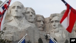 FILE - Flags frame the presidents on the Mount Rushmore monument near Keystone, South Dakota.