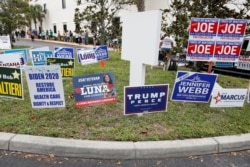 FILE - Campaign signs are posted near the Supervisor of Elections Office polling station while people line up for early voting in Pinellas County ahead of the election in Largo, Florida, October 21, 2020.