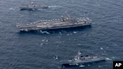 FILE - The Navy's forward-deployed aircraft carrier USS Ronald Reagan, center, and the forward-deployed Arleigh Burke-class destroyer USS Stethem, left, steam alongside ships from the South Korean navy during joint naval drills, Oct. 18, 2017, east of the Korean Peninsula.