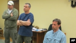 In this handout photo provided by the FSB, a man claimed by FSB to be Ryan Fogle, right, a third secretary at the U.S. Embassy in Moscow, with Embassy officials at left, sits in the the FSB offices in Moscow, early Tuesday, May 14, 2013.